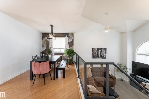 Open-concept dining area featuring wood-finish flooring, a contemporary chandelier, and a decorative accent wall - 183 Dechene Road, Edmonton, AB 