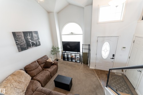 Two-story living area featuring vaulted ceilings, an arched window, a transom window, and an entry door with an oval-leaded glass insert - 183 Dechene Road, Edmonton, AB 
