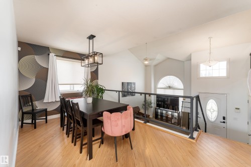 Dining area featuring wood-finish flooring and a contemporary geometric accent wall - 183 Dechene Road, Edmonton, AB 