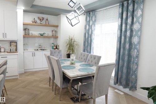 Dining area featuring a contemporary chandelier, herringbone wood-finish flooring, and built-in cabinetry with open shelving - 17703 74 Street, Edmonton, AB 