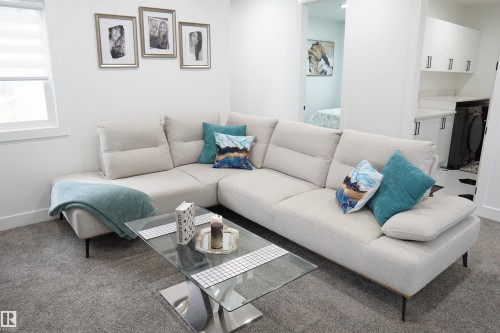 Spacious living area featuring neutral carpeting and a modern glass-top coffee table - 17703 74 Street, Edmonton, AB 