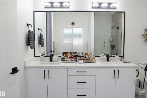 Double vanity with integrated sinks, white cabinetry, quartz countertop, and black fixtures - 17703 74 Street, Edmonton, AB 