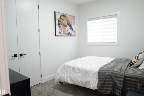 Neutral-toned room featuring a single window with blinds, carpeted flooring, and a pair of white paneled doors with matte black hardware - 17703 74 Street, Edmonton, AB 