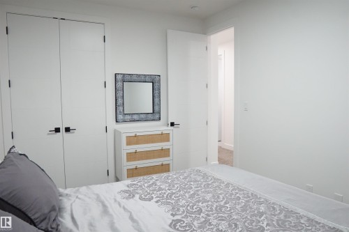 Recessed lighting illuminates a space featuring a white door with matte black hardware, a built-in closet with double doors, and a doorway opening to an interior hallway with carpeted flooring - 17703 74 Street, Edmonton, AB 