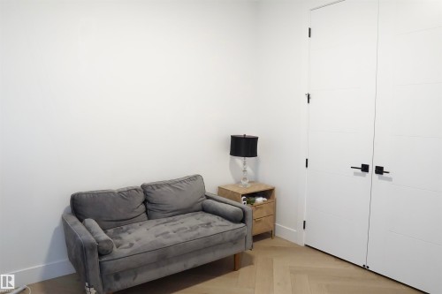 Herringbone wood-finish flooring complements the crisp white walls and modern white doors, featuring black hardware - 17703 74 Street, Edmonton, AB 