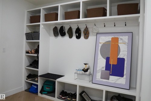 Built-in white storage unit featuring multiple open shelves, integrated coat hooks, and a bench with shoe storage below - 17703 74 Street, Edmonton, AB 