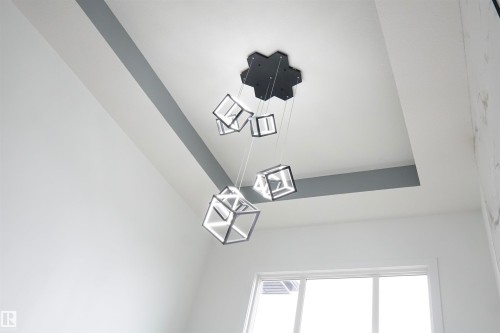 Contemporary chandelier with cubic pendants suspended from a black hexagonal base, set against a white ceiling with gray accent stripes - 17703 74 Street, Edmonton, AB 