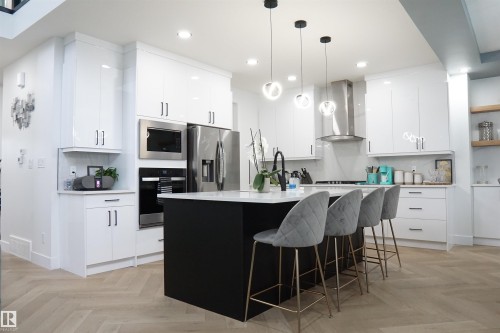 Modern kitchen featuring a black central island with a white countertop - 17703 74 Street, Edmonton, AB 