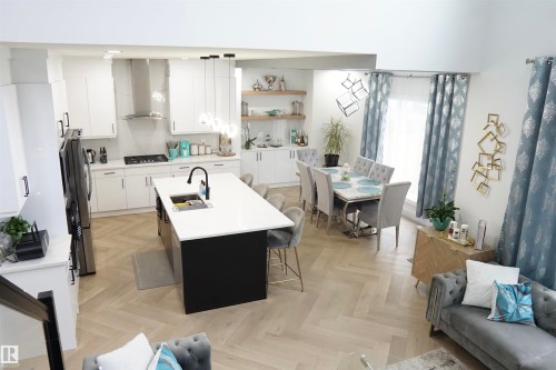 Open-concept living space with herringbone wood-finish flooring, a contemporary kitchen, and a dining area - 17703 74 Street, Edmonton, AB 