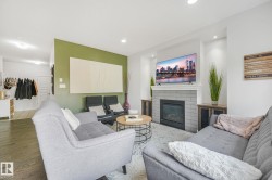 Contemporary living space featuring a tiled fireplace with mantel, recessed lighting, and rich wood-finish flooring - 