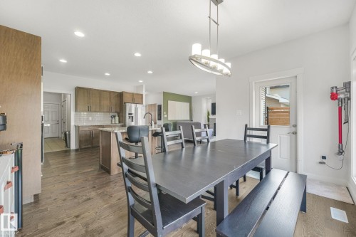 Open-concept dining area with wood-finish flooring, recessed lighting, and a modern chandelier - 556 Merlin Landing Landing, Edmonton, AB 