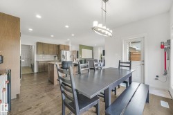 Open-concept dining area with wood-finish flooring, recessed lighting, and a modern chandelier - 