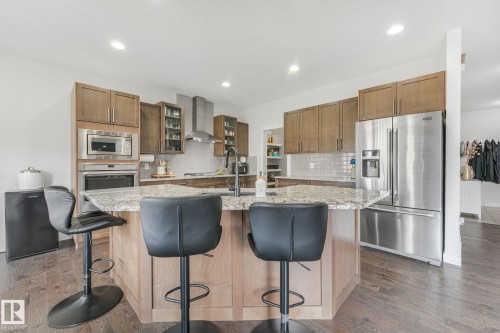 Kitchen featuring a central island with a light-toned countertop, wood-finish flooring, recessed lighting, and stainless steel appliances - 556 Merlin Landing Landing, Edmonton, AB 