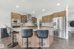 Kitchen featuring a central island with a light-toned countertop, wood-finish flooring, recessed lighting, and stainless steel appliances - 