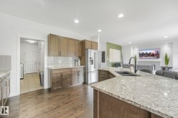 Kitchen featuring an extended island with a built-in sink, stainless steel appliances, wood-finish cabinetry, and a subway tile backsplash - 