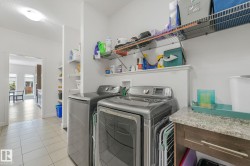 Dedicated laundry space featuring a side-by-side washer and dryer, tile flooring, and integrated wire shelving for storage - 