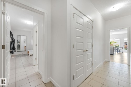 Hallway featuring light-toned tile flooring, white paneled doors, and recessed lighting - 556 Merlin Landing Landing, Edmonton, AB 