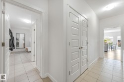 Hallway featuring light-toned tile flooring, white paneled doors, and recessed lighting - 