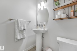 Pedestal sink with chrome fixtures and an oval mirror, complemented by an overhead vanity light - 