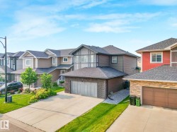Contemporary detached home featuring a brown and gray exterior with stone accents, a two-car garage, and a concrete driveway - 