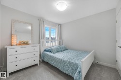 Bedroom featuring a window with exterior scenery, light gray walls, textured gray carpeting, a single ceiling light fixture, and white baseboards - 