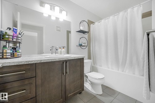 Modern bathroom featuring a double vanity with dark wood cabinetry, a light-colored countertop, and dual sinks - 556 Merlin Landing Landing, Edmonton, AB 