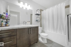 Modern bathroom featuring a double vanity with dark wood cabinetry, a light-colored countertop, and dual sinks - 