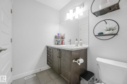Modern bathroom featuring a double vanity with a light-colored countertop, dual undermount sinks, and contemporary silver-toned fixtures - 