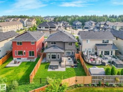 Expansive backyard featuring a manicured lawn, a wooden privacy fence, a multi-level wooden deck, and a hot tub - 