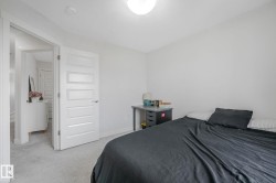 Bedroom with light gray carpeting and a white door featuring five recessed panels - 