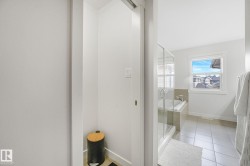 Bathroom featuring a glass-enclosed shower, a built-in tub with tile surround, a large window, and tile flooring - 