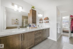 Dual vanity with granite-finish countertop, wood-finish cabinetry, and contemporary lighting fixtures - 