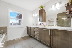 Bathroom featuring a double vanity with light-toned countertops, integrated sinks, and dark wood-finish cabinetry - 