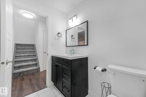Bathroom featuring a black vanity with white countertop, rectangular mirror, and wall-mounted light fixture - 556 Merlin Landing Landing, Edmonton, AB 