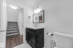 Bathroom featuring a black vanity with white countertop, rectangular mirror, and wall-mounted light fixture - 