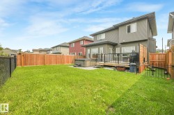 Expansive backyard featuring a large green lawn, full privacy fencing, and a multi-level wood deck - 