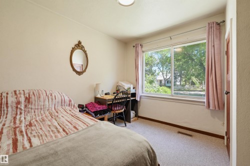 Bedroom space featuring a large window, light-colored walls, and neutral carpet flooring - 11414 88 Street Nw, Edmonton, AB 