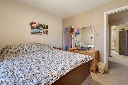 Neutral tone wall paint with matching trim, carpeted flooring, and a doorway opening to an additional room - 