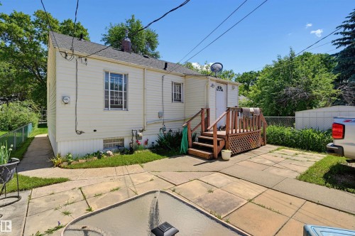 Rear exterior featuring light-colored siding and a wooden deck with lattice detailing - 11414 88 Street Nw, Edmonton, AB 
