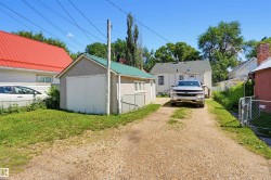 Gravel driveway providing access to a detached garage with a green metal roof and a white overhead door - 