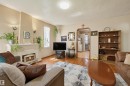 Living area featuring wood-finish flooring, a decorative fireplace with a mantel, recessed wall sconces, and a built-in shelving unit - 11414 88 Street Nw, Edmonton, AB 