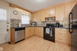 Kitchen featuring light wood-finish cabinetry, dark countertops, and a mosaic tile backsplash - 