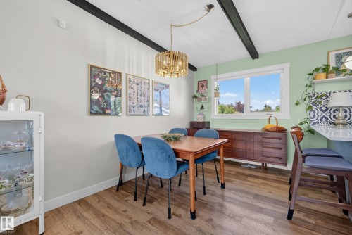 Dining space featuring wood-finish flooring, exposed ceiling beams, and a modern gold-tone chandelier - 14128 73 Street, Edmonton, AB 