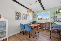Dining space featuring wood-finish flooring, exposed ceiling beams, and a modern gold-tone chandelier - 