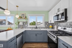 Kitchen featuring light green walls, a black and white patterned tile backsplash, white countertops, and wood-finish flooring - 
