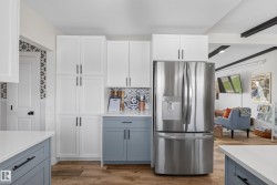 Kitchen featuring white shaker cabinetry, contrasting blue lower cabinetry, and a stainless steel French door refrigerator - 