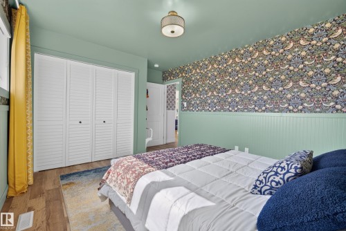 Bedroom featuring wood-finish flooring, a decorative ceiling fixture, and bi-fold louvered closet doors - 14128 73 Street, Edmonton, AB 