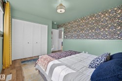 Bedroom featuring wood-finish flooring, a decorative ceiling fixture, and bi-fold louvered closet doors - 