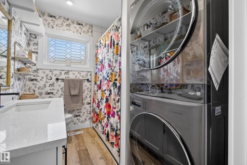 Bathroom featuring a white quartz-style countertop, a rectangular undermount sink with a matte black faucet, and patterned wallpaper - 14128 73 Street, Edmonton, AB 