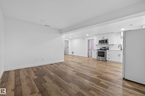 Open concept living area featuring wood-finish flooring, white walls, and recessed lighting - 14128 73 Street, Edmonton, AB 